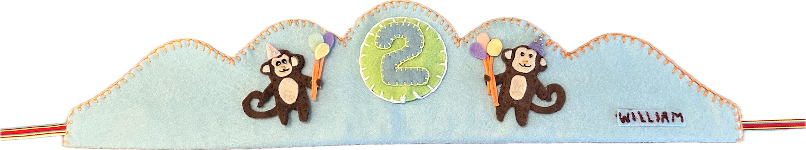 Pale-blue felt crown with two brown felt monkeys in party hats holding balloons, a green number 2 patch in the middle, and the name William stitched on a small label.